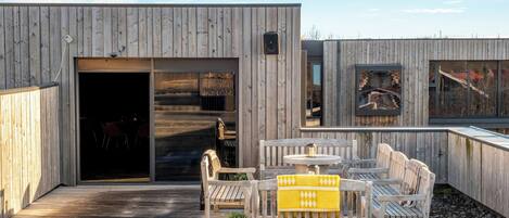 A wooden deck with outdoor furniture, a sliding glass door, and a small outdoor kitchen area.