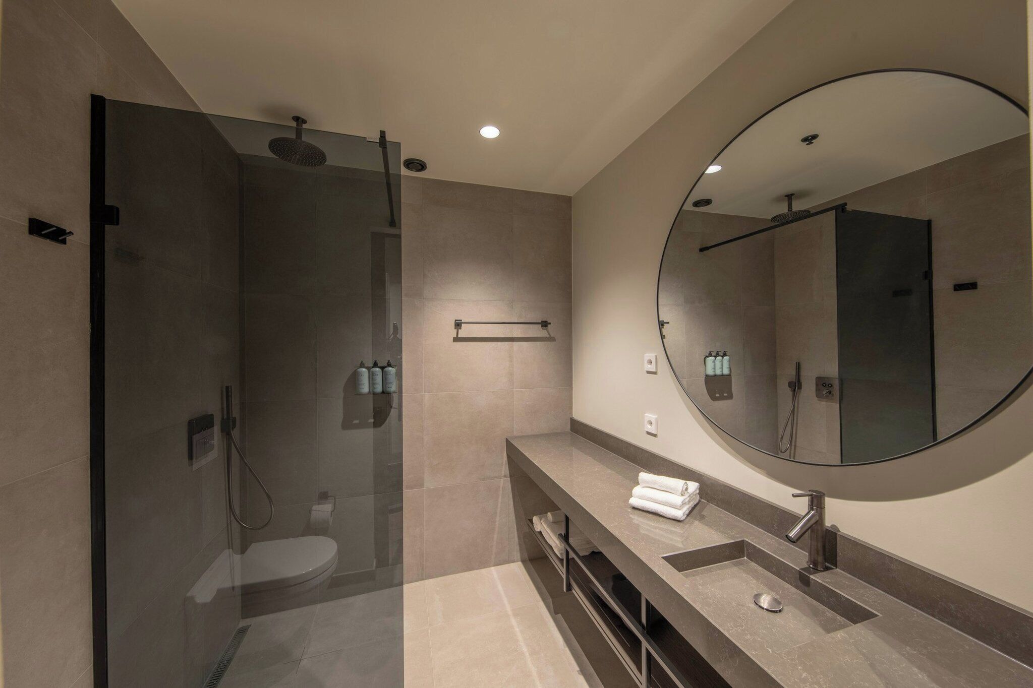 Une salle de bain moderne avec une douche à parois de verre, un meuble-lavabo et un grand miroir.