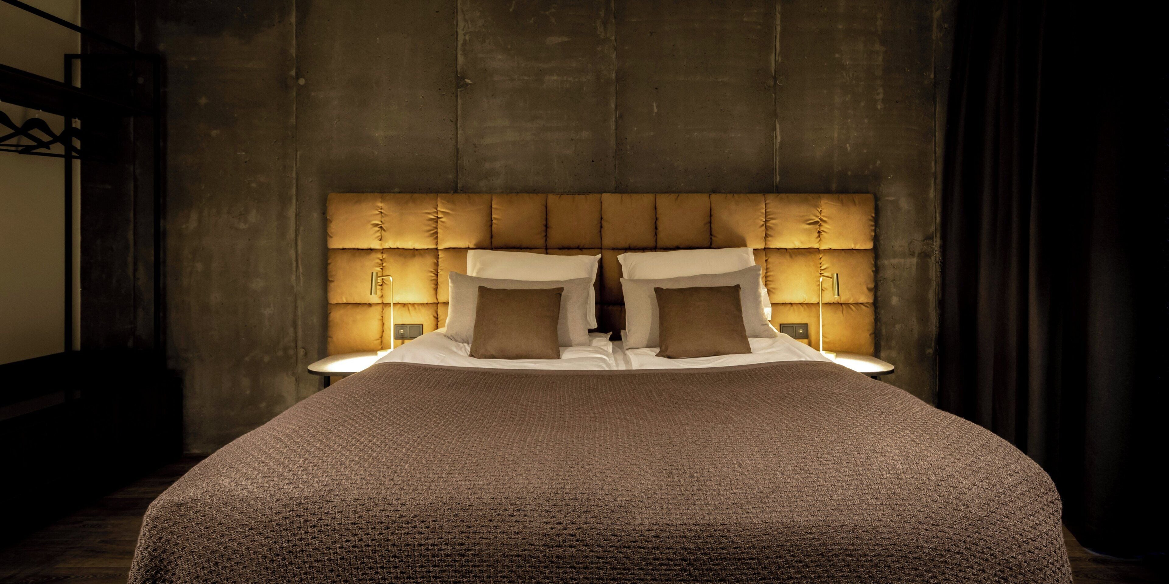 A large bed with a tufted headboard, multiple pillows, and bedside lamps.