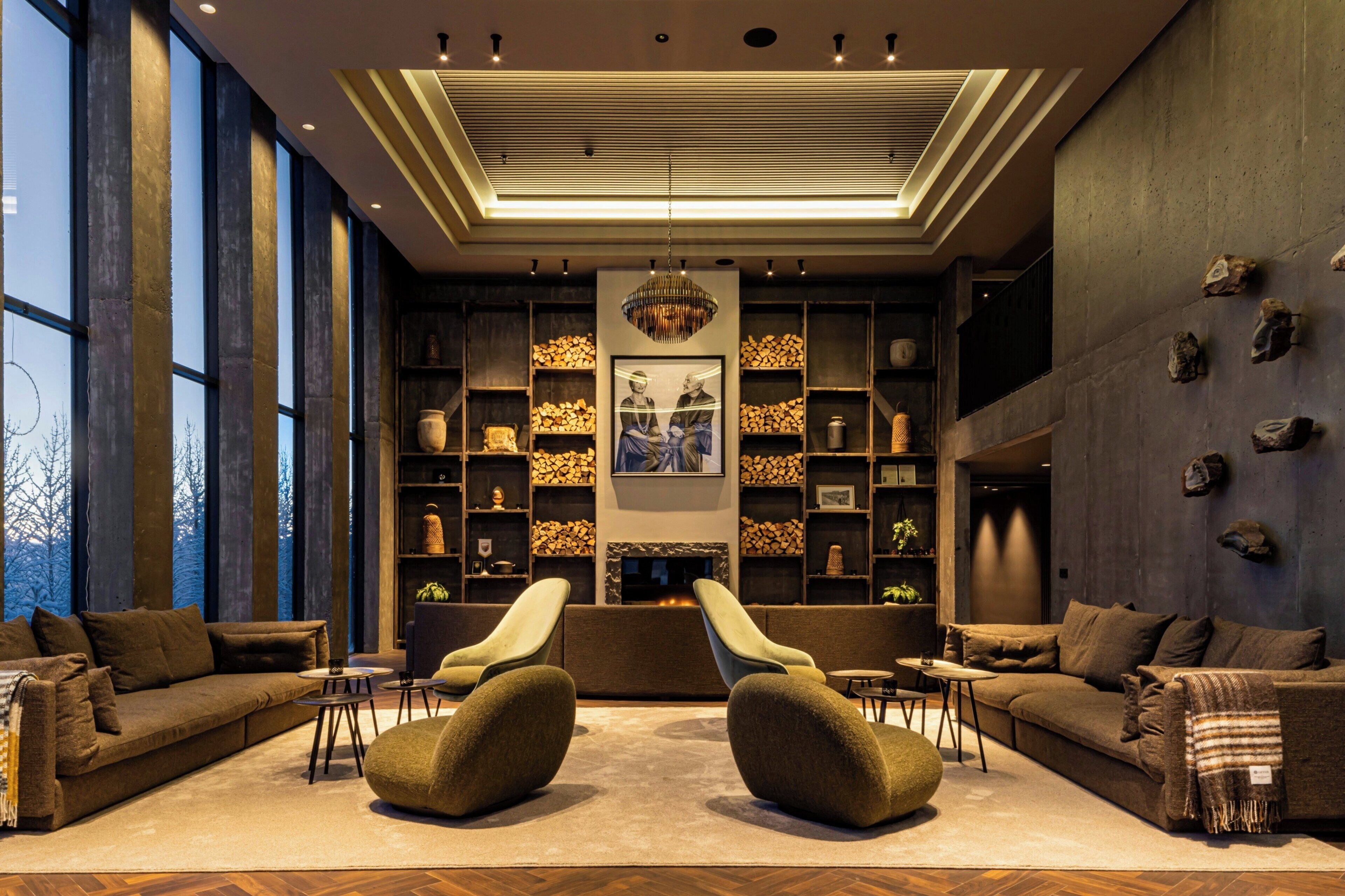 A modern interior with a fireplace, seating area, and large windows.