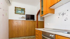 Una cocina con armarios de madera, horno empotrado y salpicadero de azulejos.