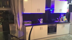 A modern kitchen with white cabinets, a black countertop, and blue under-cabinet lighting. - Paisley central luxury Rooms & Apartment (Paisley)
