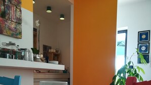 Ein Essbereich mit einem Tisch für zwei Personen, einem Croissant auf einem Teller, einer weißen Tasse und einer Pflanze im Hintergrund.