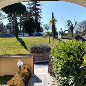 Un estacionamiento con varios autos, un área verde y una entrada a un edificio.