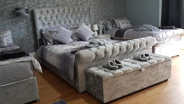 A bedroom with a large bed, two bedside tables, a bench, and a headboard. - Crossroad Bungalow (Paisley)