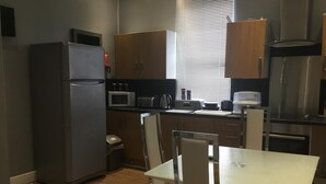 A compact kitchen with a refrigerator, microwave, toaster, and a sink. - Crossroad Bungalow (Paisley)