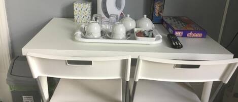 A white table with a tea set, a chess board, and a remote control.