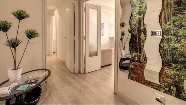 A modern interior with a curved wall feature, a hallway leading to a living area, and a dining table with a plant. - Retro2 Vaticano-max 4 pax (Rome)