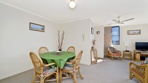 A room with a dining table, chairs, a television, and a ceiling fan. - Sundial 602, Hollingworth Street (Port Macquarie)