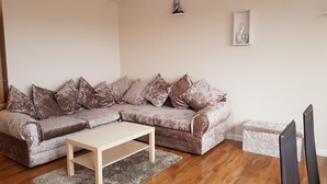 Ein Wohnzimmer mit einer Eckcouch, einem Couchtisch und einer TV-Kommode.