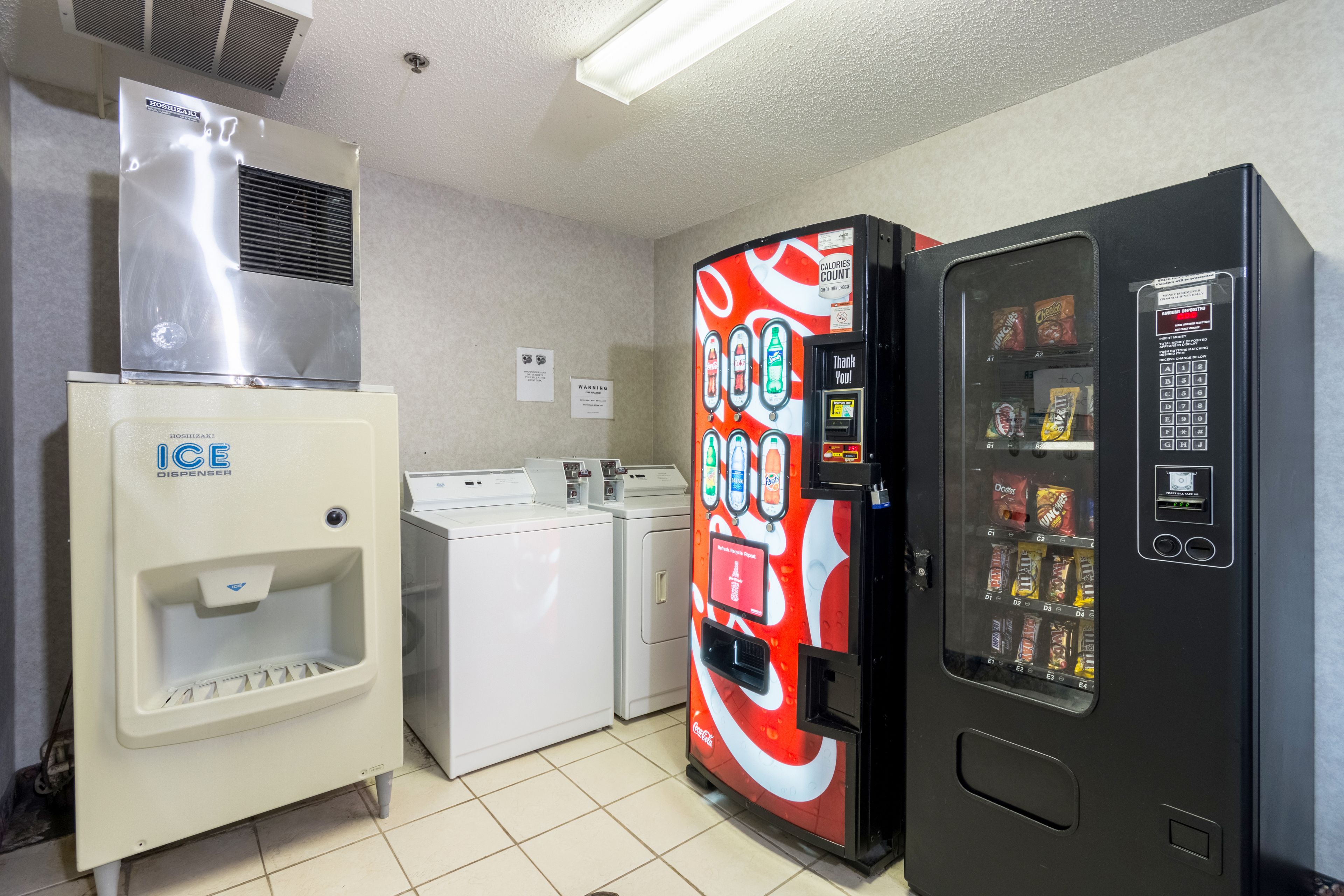 A laundry room with an ice dispenser, a vending machine, and a dryer.