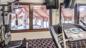 A gym with exercise equipment, large windows, and a television.