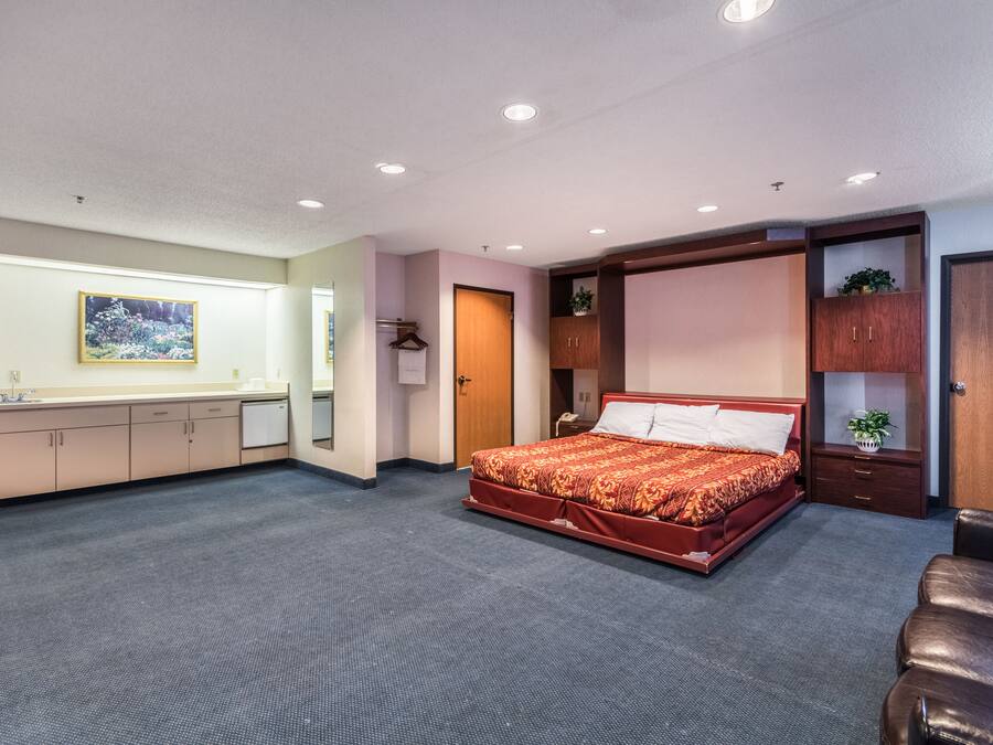 Habitación de hotel con una cama grande, un escritorio con silla, armario y baño pequeño.