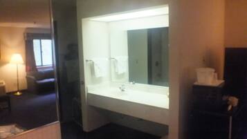 A hotel bathroom with a large mirror, a sink, and a toilet.
