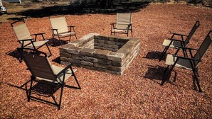 A fire pit surrounded by four chairs with metal frames and fabric seats. - Cliffside Tiny Home Container  #5 (Orderville)