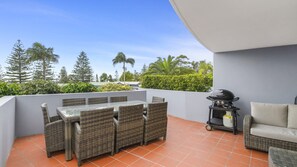 En udendørs terrasse med spisebord og stole, grill og sofa.