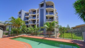 Un hôtel à plusieurs étages doté de balcons, d’une piscine et d’une végétation tropicale.