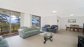 A spacious living area with a sofa, two armchairs, a glass coffee table, and a dining table with chairs.