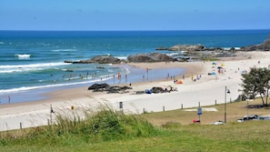 Uma praia com pessoas, guarda-sóis e pedras.