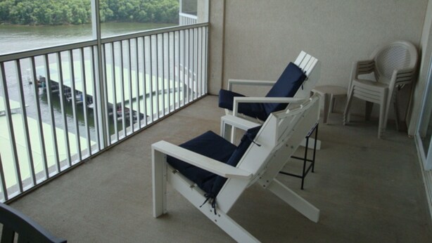 A balcony with two white lounge chairs and a small table, overlooking a body of water and greenery. - 9104 Towers, Fantastic lake views!  STILL AVAILABLE FOR SHOOTOUT RACE WEEKEND (Osage Beach)