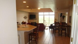 Eine geräumige Küche mit einer großen Kochinsel, ein Essbereich mit Stühlen sowie ein Wohnzimmer mit einer Couch.