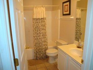 A small bathroom with a toilet, sink, and shower curtain.