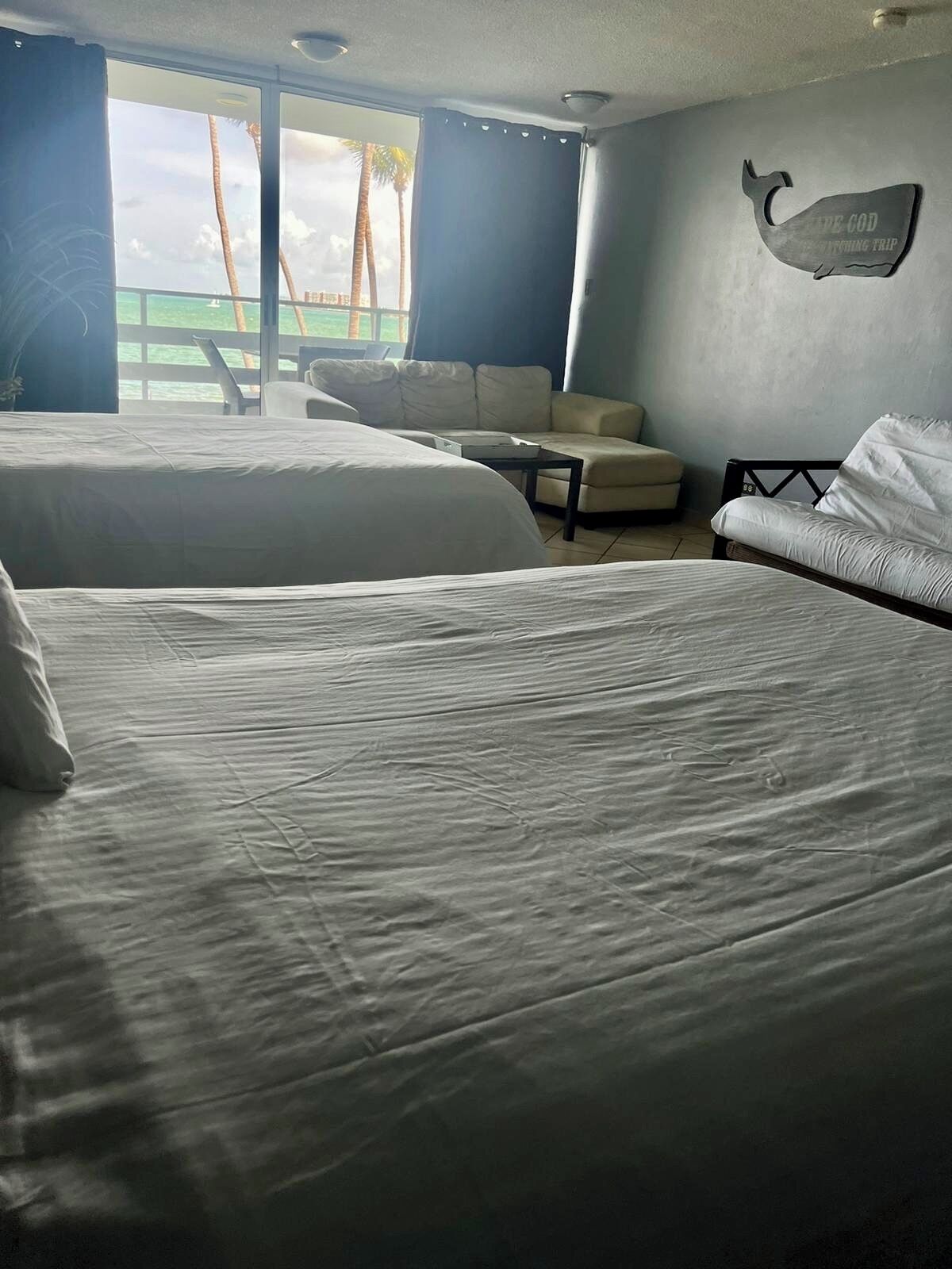A hotel room with two beds, a sofa, and a view of the ocean.