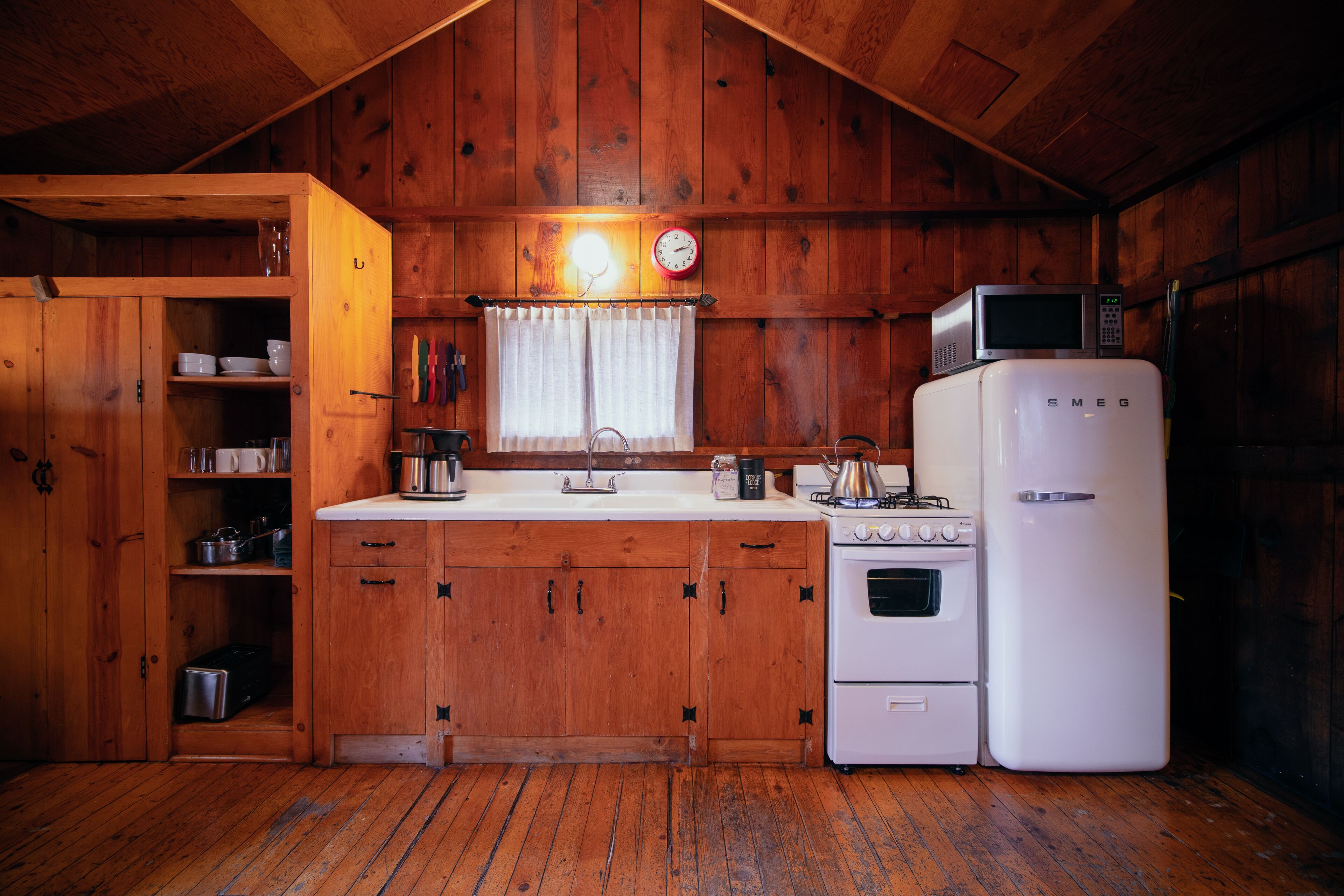 A wooden cabin kitchen with a white refrigerator, stove, and microwave.