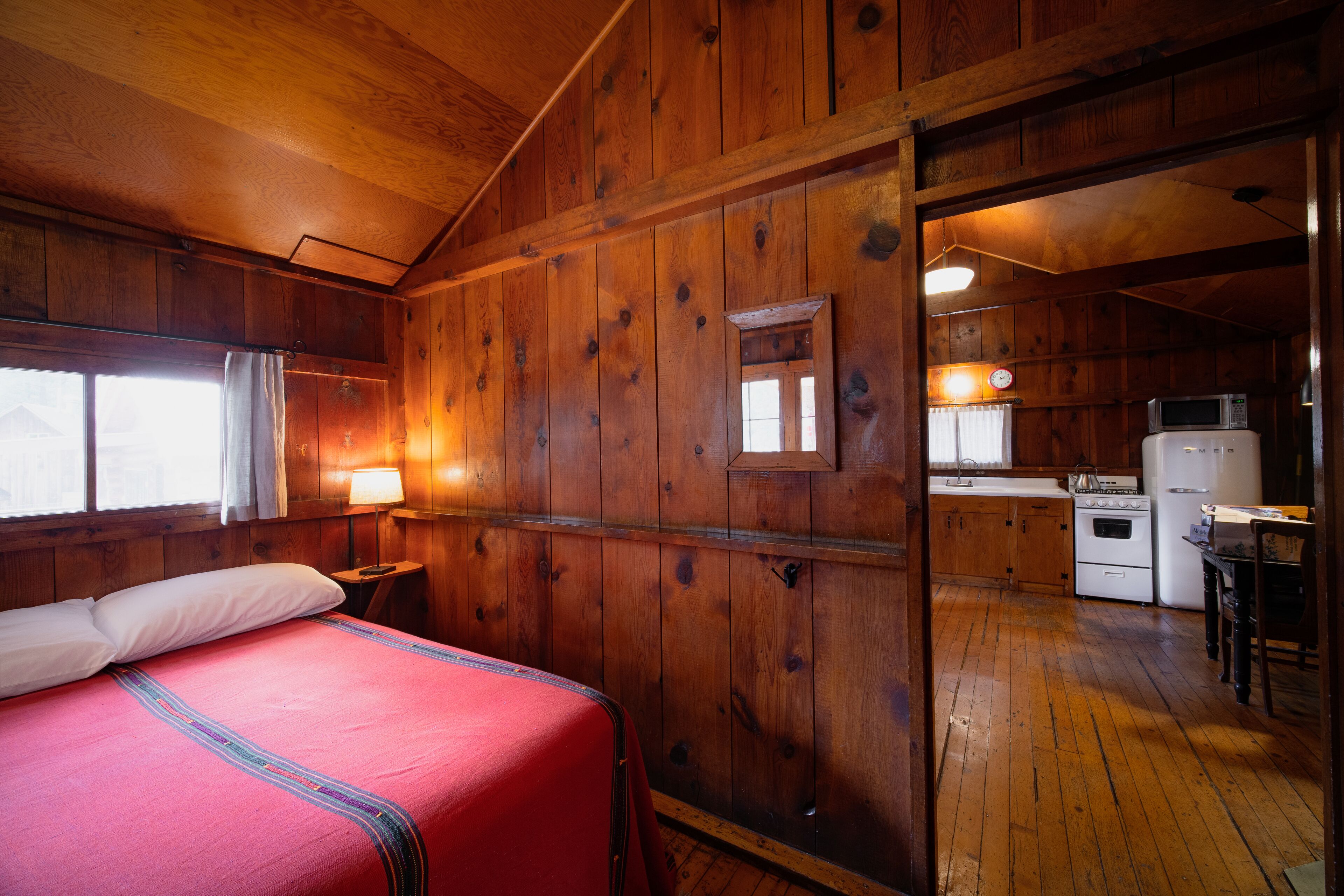 A wooden cabin with a bed, a kitchen, and a dining area.