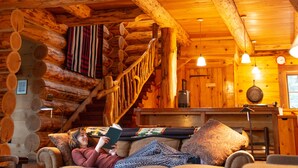 A log cabin interior with a cozy living area, a staircase, and a dining area. - Corkins Lodge (Chama)