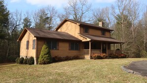A two-story wooden house with a porch, surrounded by trees and a grassy yard. - Peaceful 3BR 2.5 Bath Home Near Sparta NC & Blue Ridge Parkway Sleeps 6 (Glade Valley)