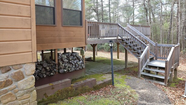 A wooden cabin with a stone foundation, a wooden deck, and a staircase leading to a deck area. - Peaceful 3BR 2.5 Bath Home Near Sparta NC & Blue Ridge Parkway Sleeps 6 (Glade Valley)