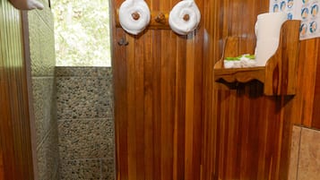 Une salle de bain avec des murs en bois, des toilettes, un lavabo et un espace douche.