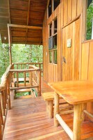 A wooden deck with benches and a railing, leading to a building with large windows.