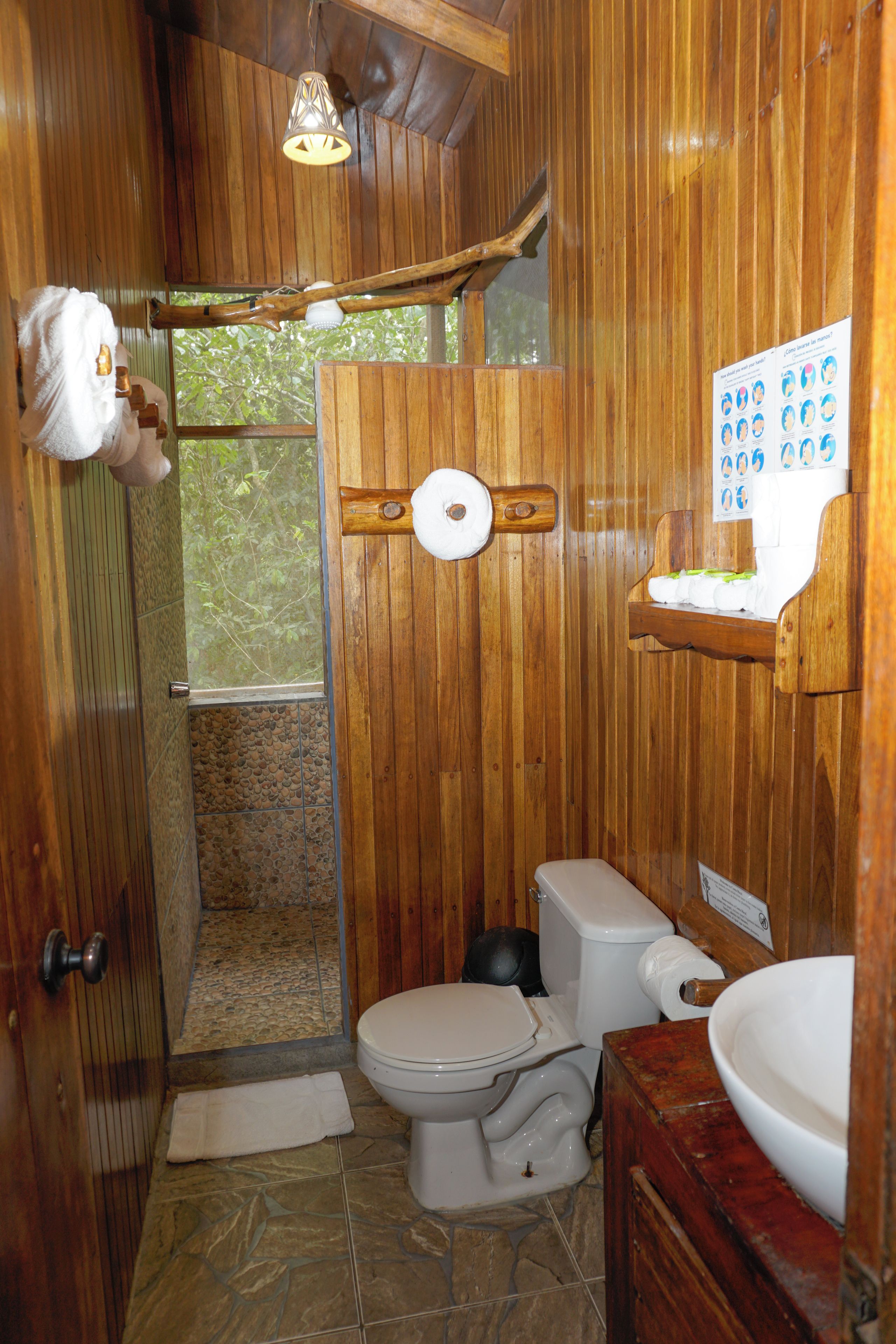 Et badeværelse i træ med toilet, vask og bruseområde.
