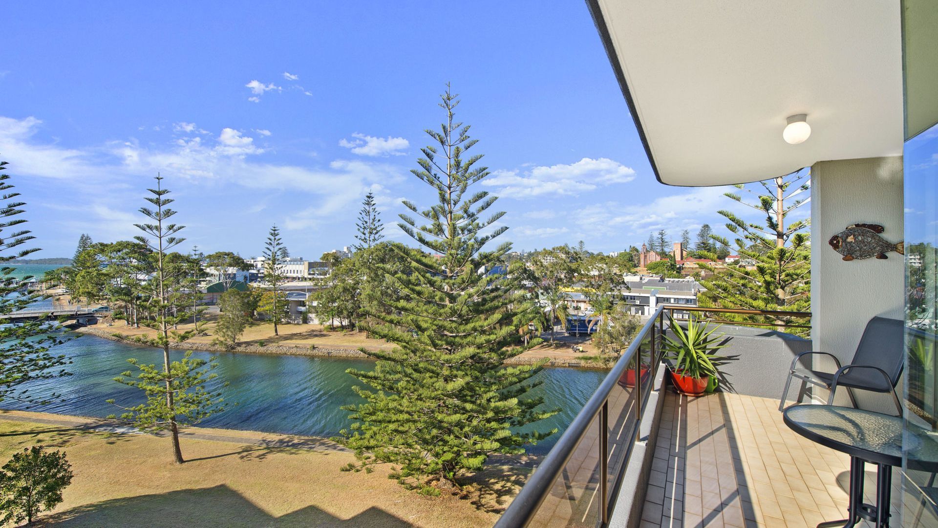 A balcony with a view of a body of water, trees, and buildings in the distance.