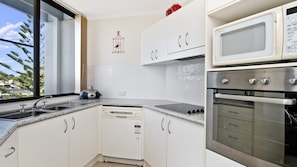 A kitchen with white cabinets, a built-in microwave, an oven, and a dishwasher. - Sundial 503, Hollingworth Street (Port Macquarie)