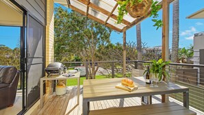 Eine Terrasse im Freien mit Grill, Esstisch und Sitzgelegenheit.
