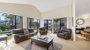 A modern living room with a glass coffee table, leather sofas, and a dining area with a wooden table and chairs. - Amara, 6 Wesley Avenue (Port Macquarie)