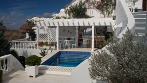 Ein weißes Gebäude mit Pool, Sitzgelegenheiten im Freien und Blick auf das Meer.