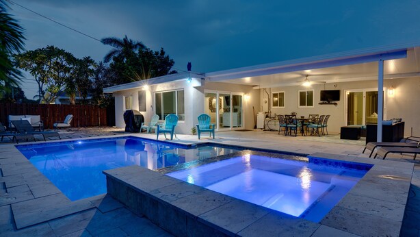Et moderne hus med swimmingpool, udendørs møbler og en patio.