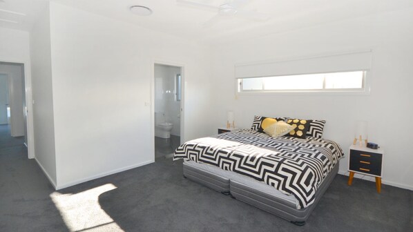A bedroom with a bed, bedside tables, a window, and a door leading to a bathroom.