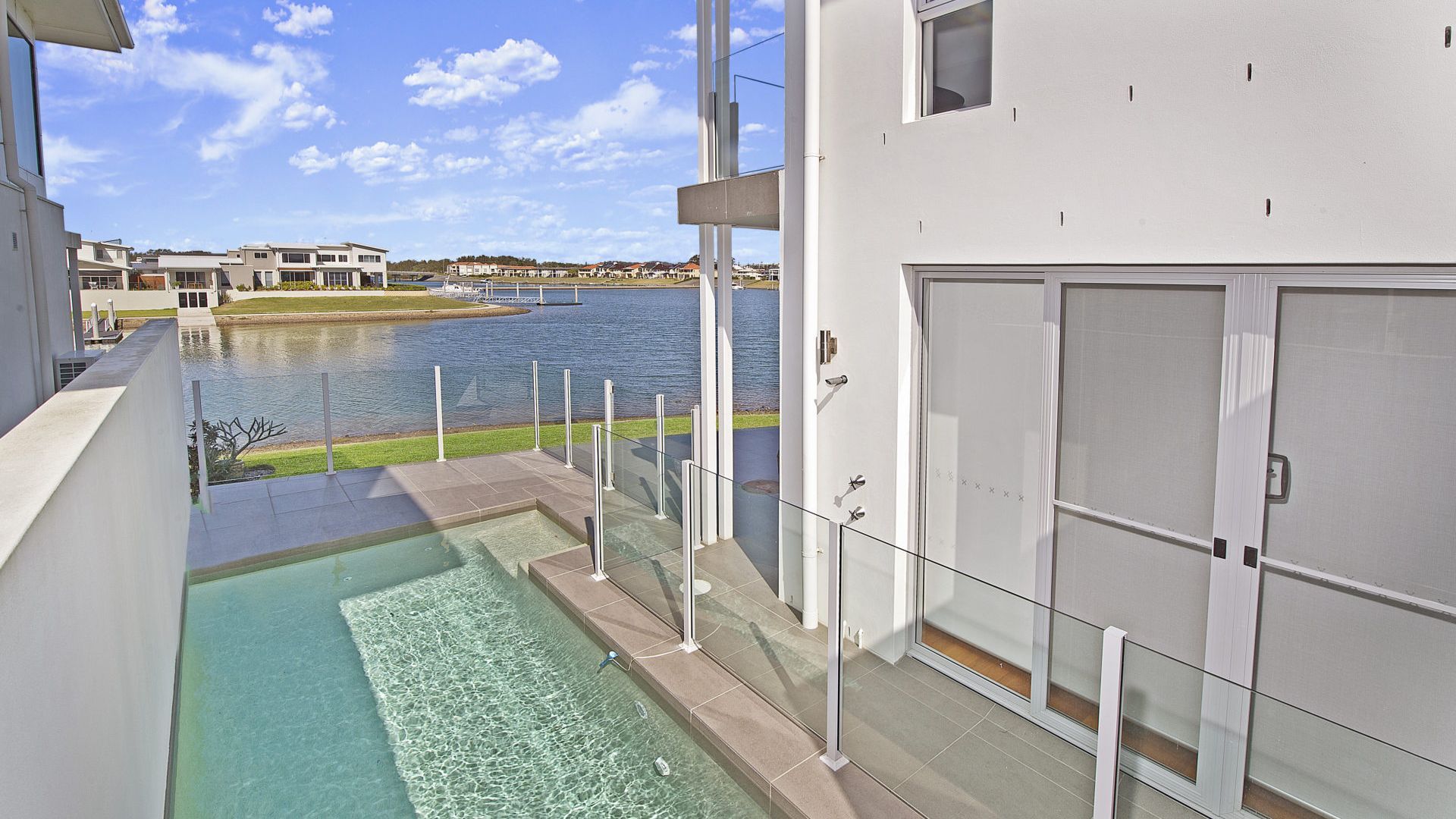 A modern building with a pool and a view of a body of water.