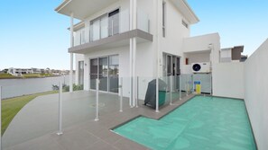 En moderne toetagers bygning med balkon, poolområde og udsigt over vandet.