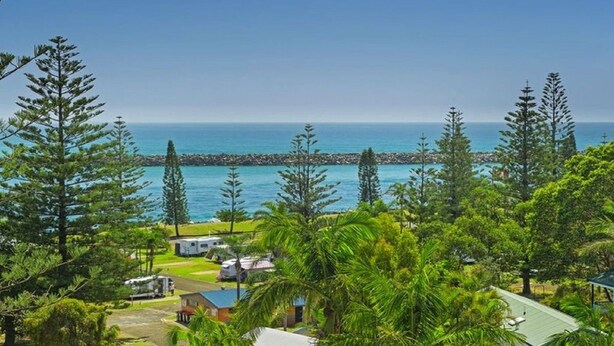 A coastal property with a view of the sea, surrounded by trees and a small building. - Flightdeck 301, Clarence Street (Port Macquarie)
