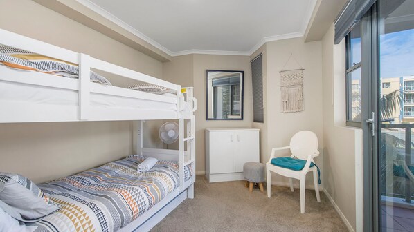 A compact room with bunk beds, a small cabinet, a chair, and a window with a view.