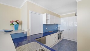 A modern kitchen with a blue countertop, white cabinets, and a built-in oven.