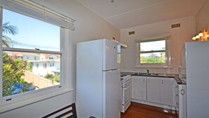 A compact kitchen with white appliances, a window, and a view of a residential area.