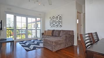 A living room with a grey sofa, a patterned rug, and a dining area with a wooden table and chairs.