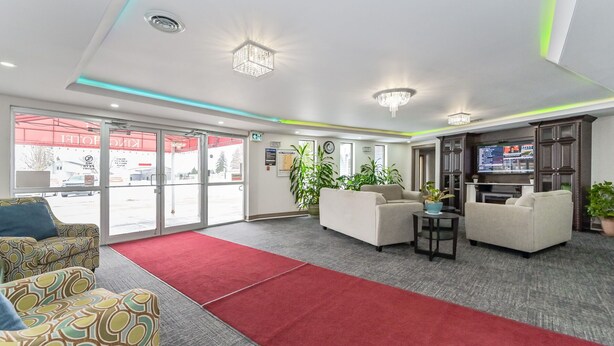 Un hall d’entrée moderne avec un tapis rouge, deux canapés, une petite table et un téléviseur.